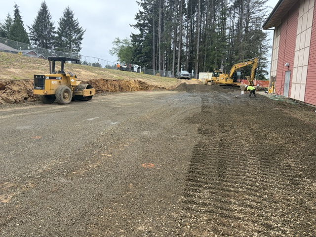 2 heavy construction equipment machines level ground by a school