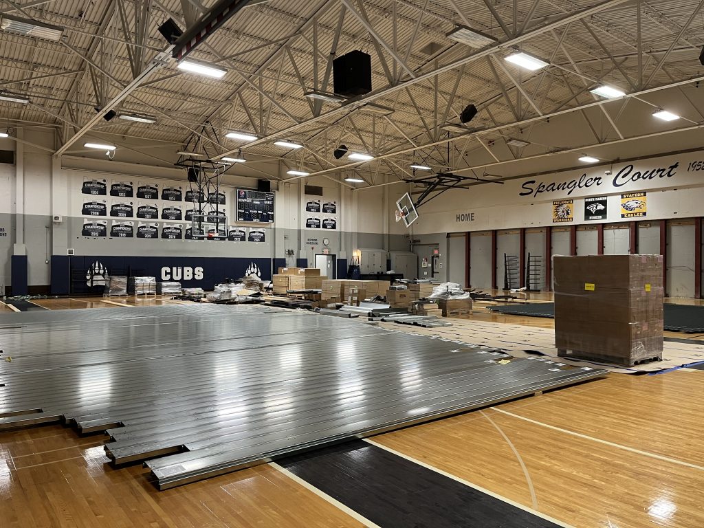 Metal bleachers laying on a gym floor with other construction materials