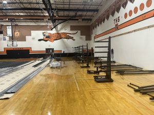 Gym with bleachers stack on wooden floor