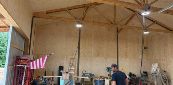 Man in a blue shirt standing in an unfinished building with construction equipment