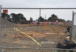 Construction equipment and dirt behind a chain link fence