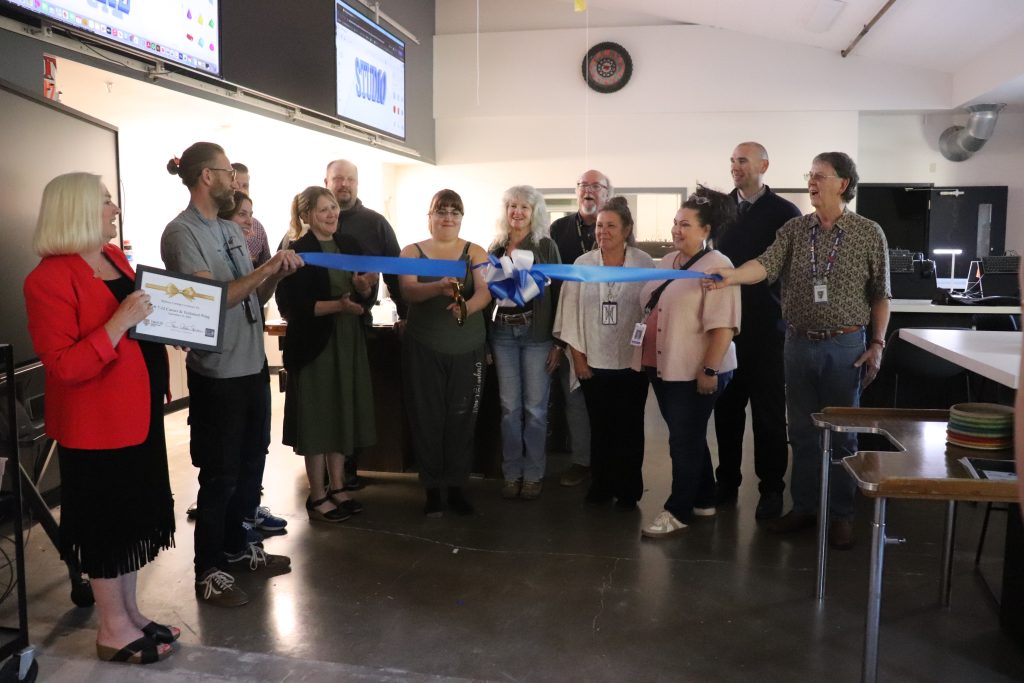 People prepare to cut a long blue ribbon