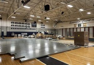Metal bleachers laying on a gym floor with other construction materials