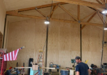Man in a blue shirt standing in an unfinished building with construction equipment