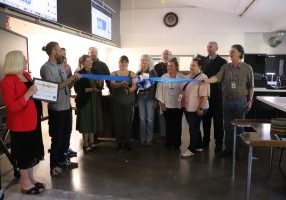 People prepare to cut a long blue ribbon